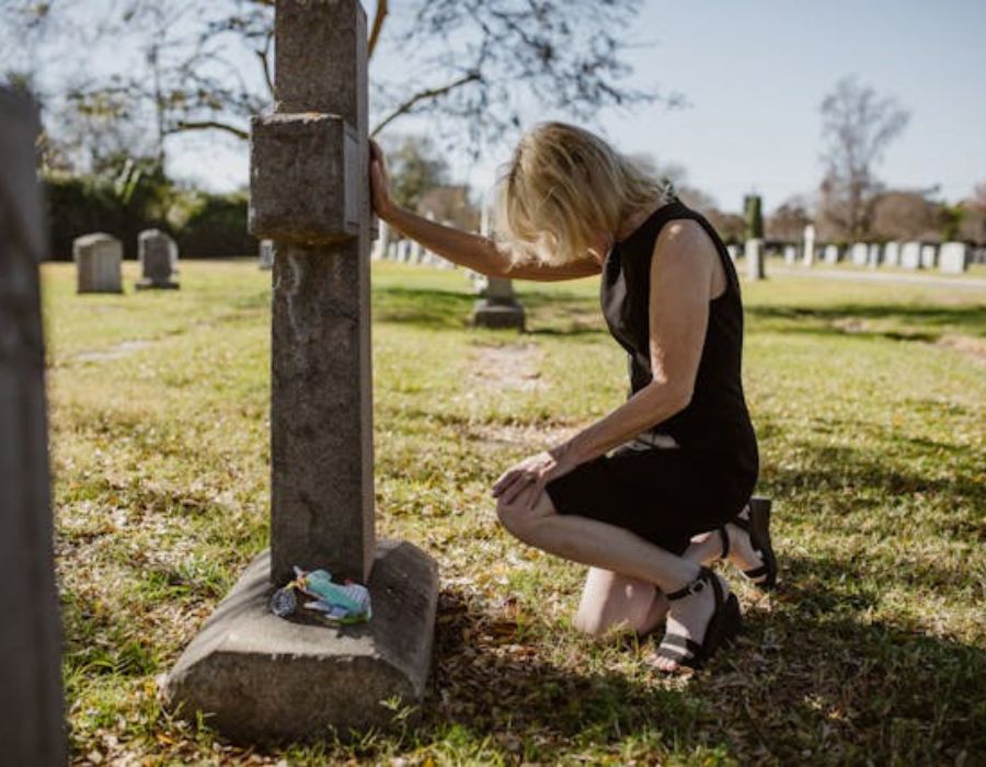 Woman Kneeling in front of Gravestone