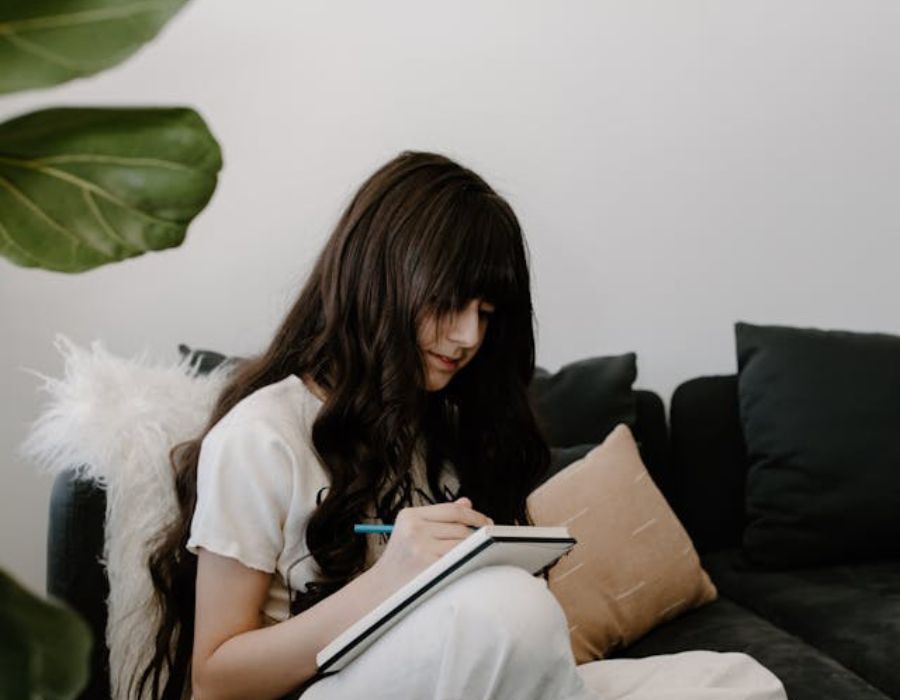 a girl writing down something on a notebook