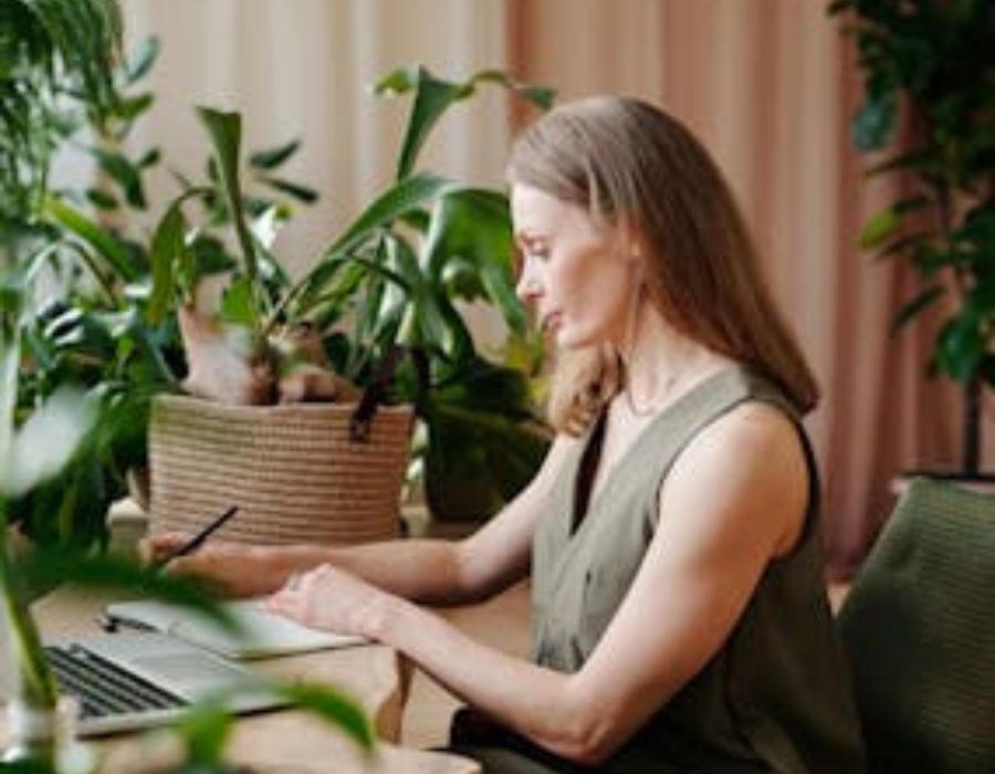 Woman in Green Sleeveless Dress Writing on a Notebook