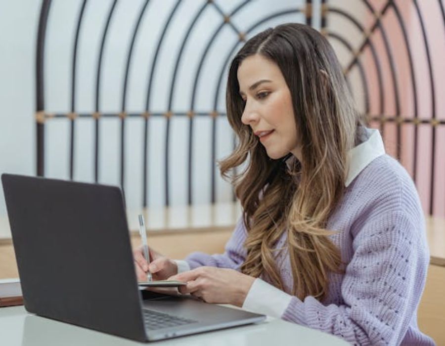 a woman writing something from the laptop