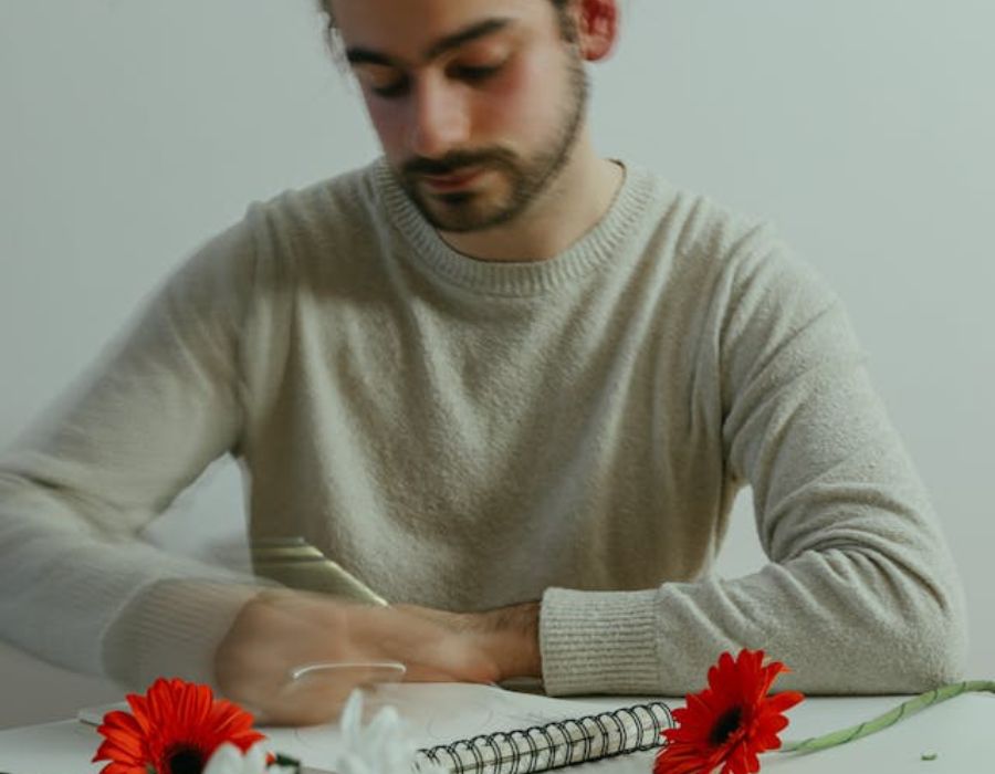 a gloomy man writing down on a piece of paper