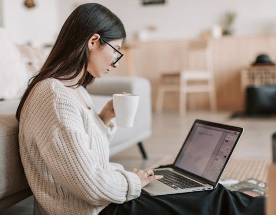 a lady going through something on the laptop while taking tea