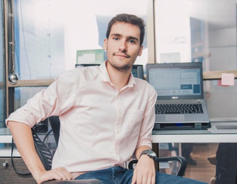 a man in an office  with a laptop in the background